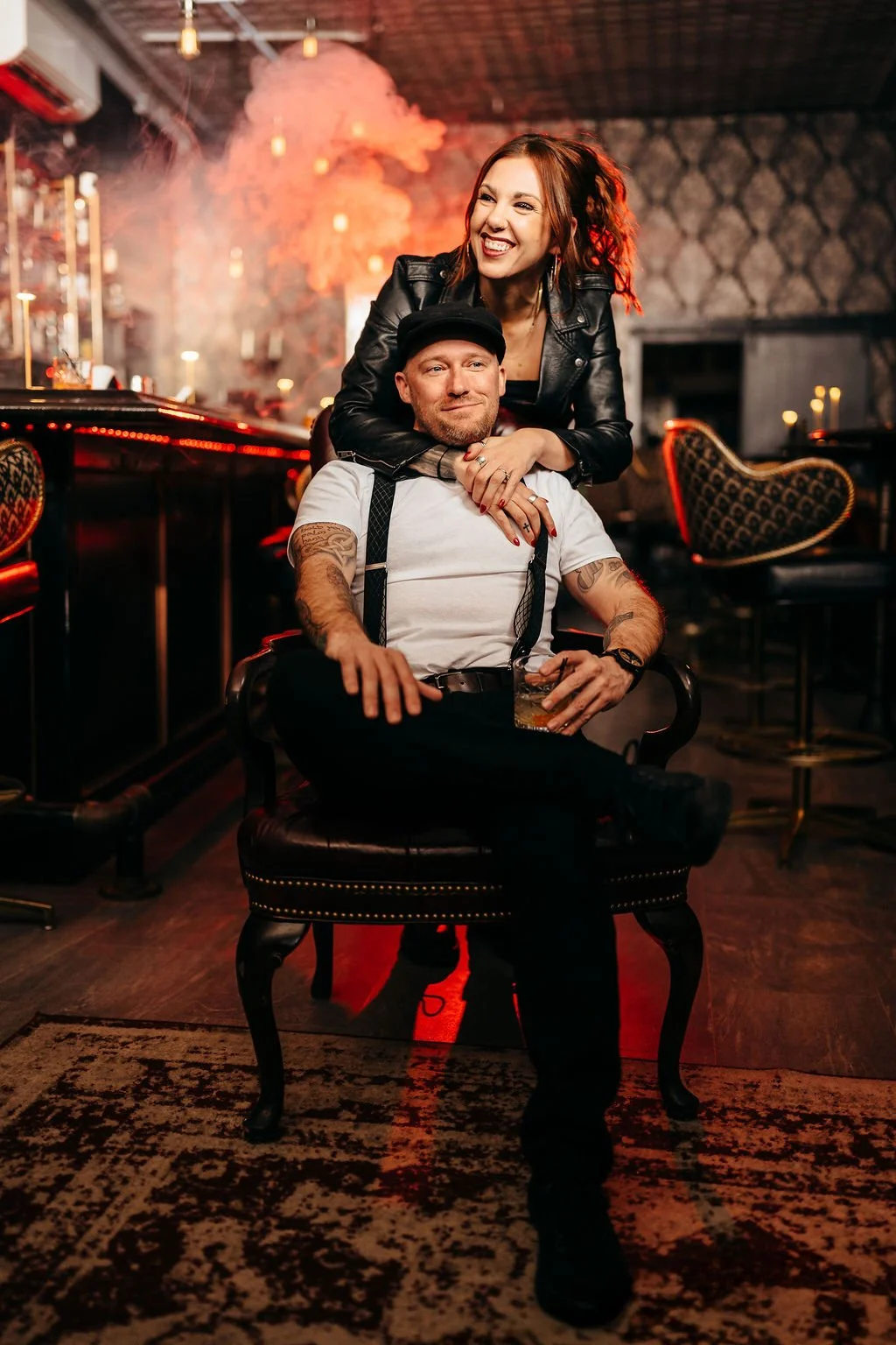 Kristin and Mike laughing in red haze at the bar during their speakeasy engagement photos