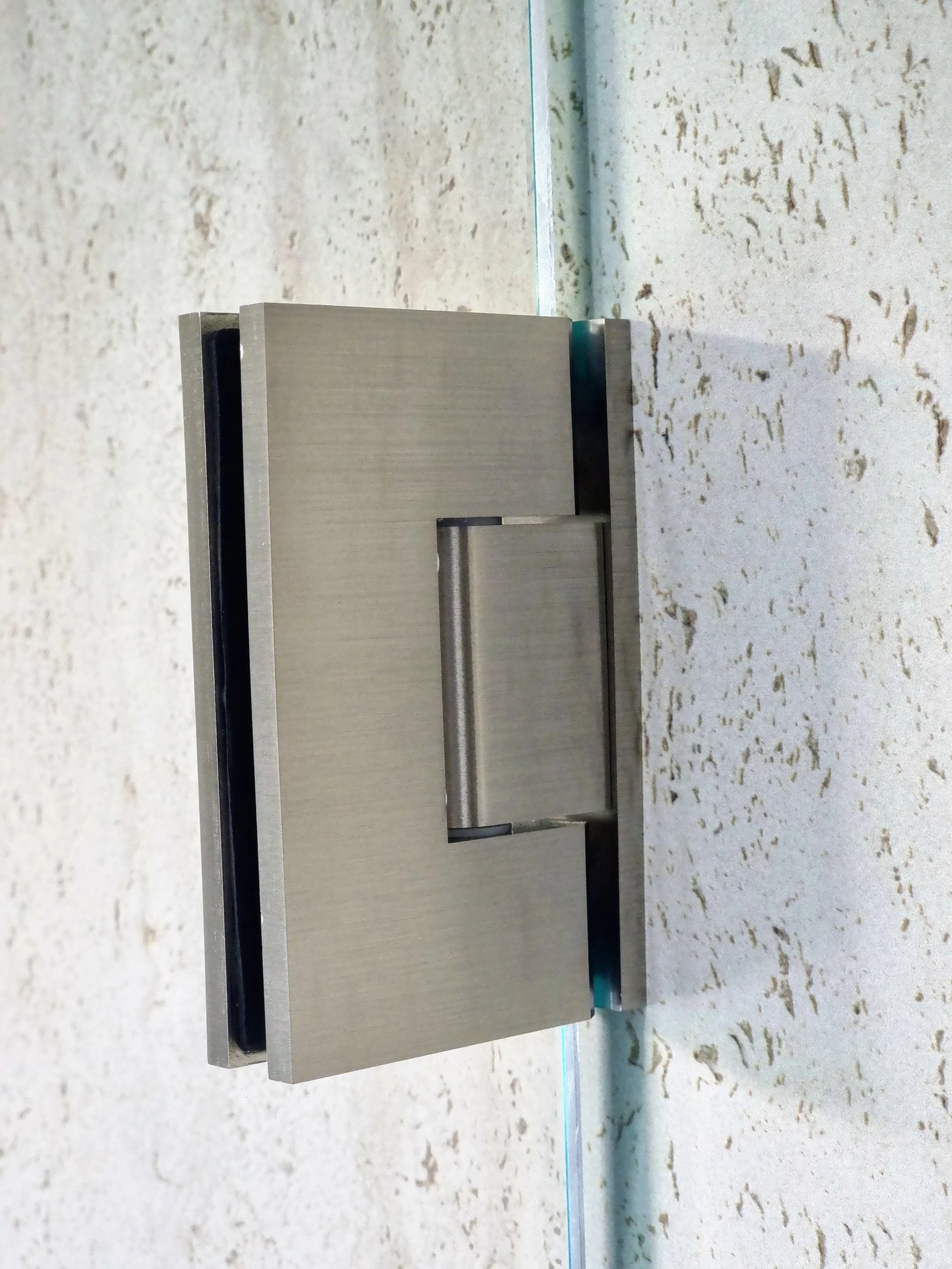 Close-up of brushed nickel frameless shower hinge detail