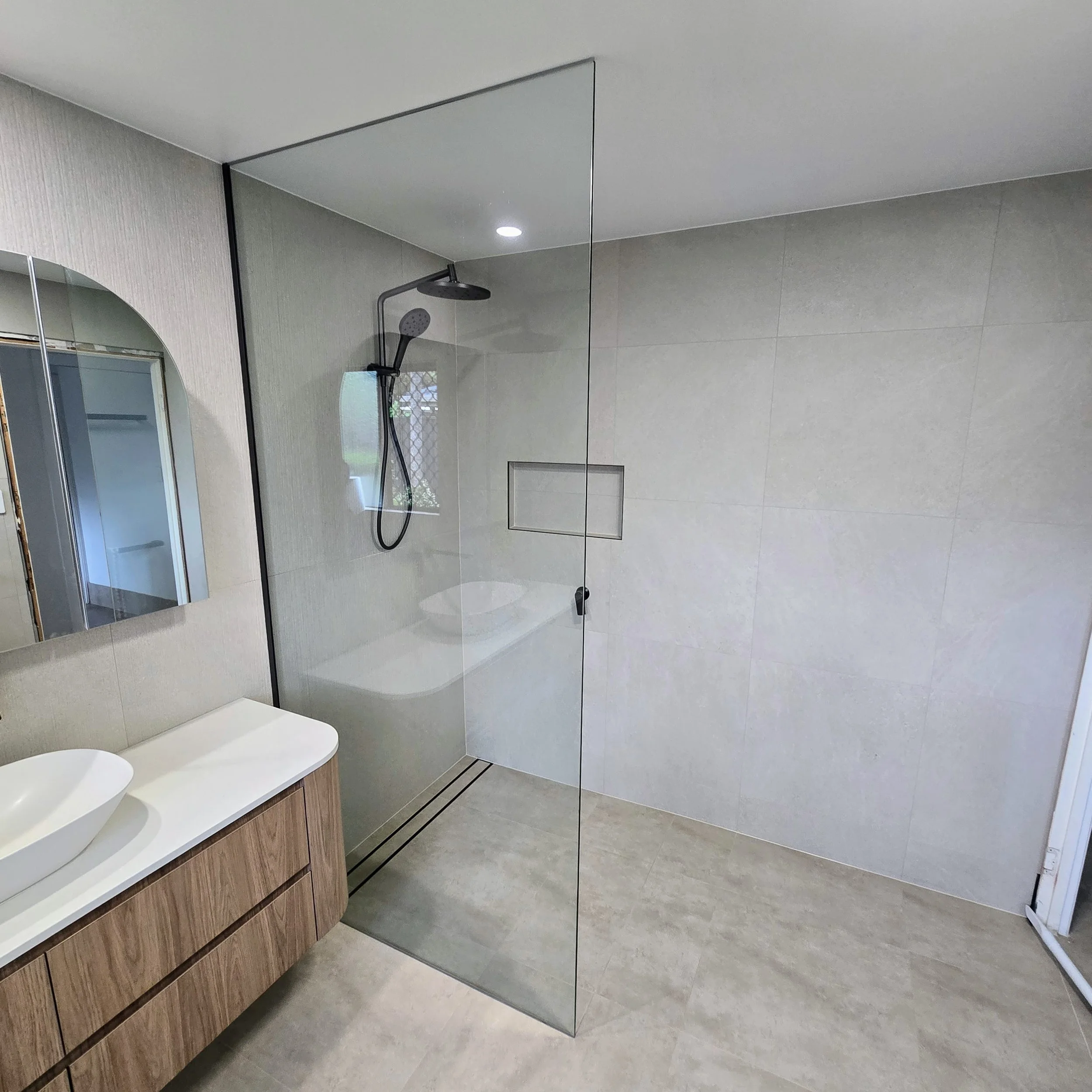Frameless fixed shower panel with clean minimal hardware in a Sunshine Coast bathroom