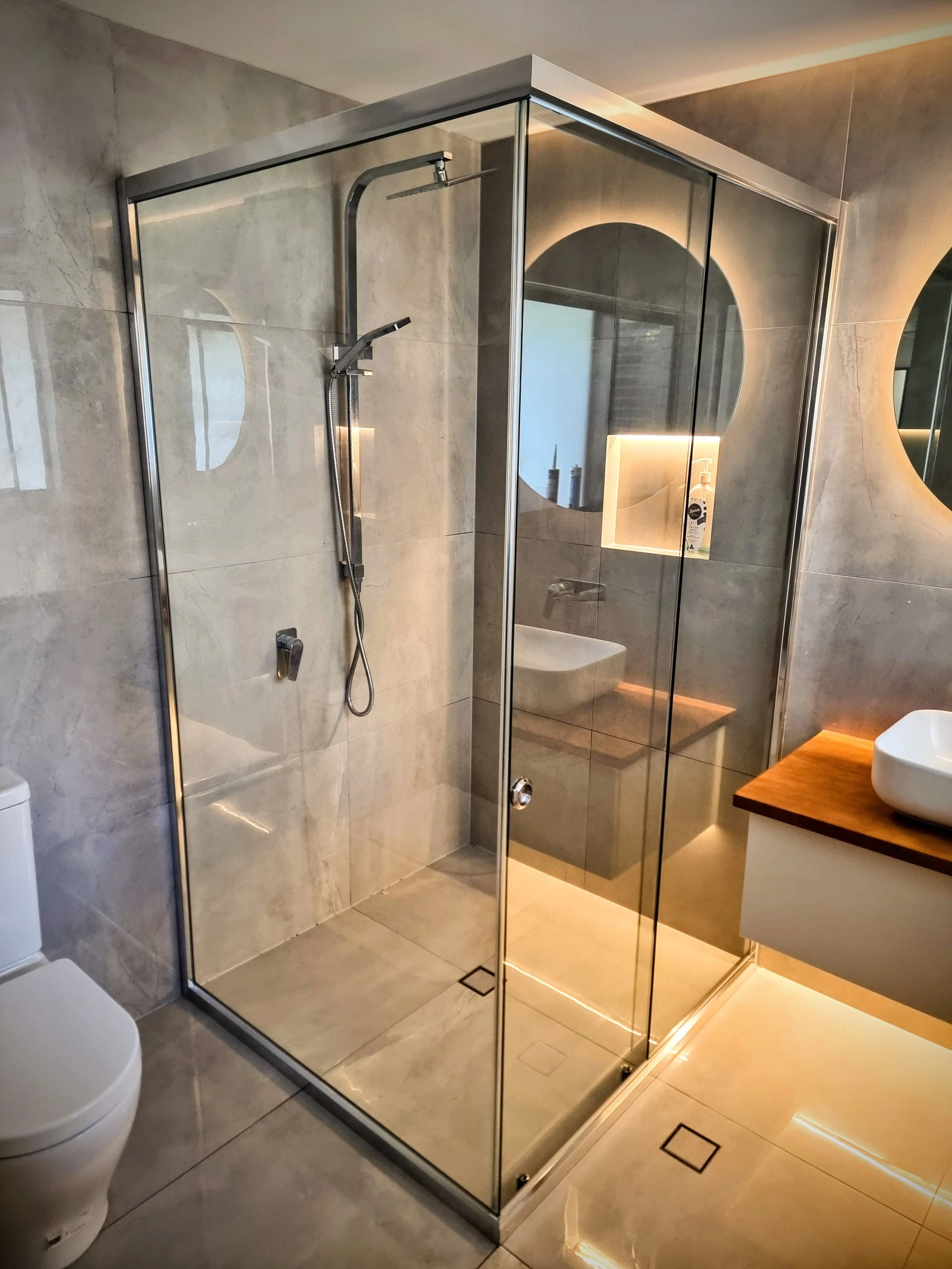 Semi-frameless sliding shower screen with smooth bypass panels in contemporary bathroom