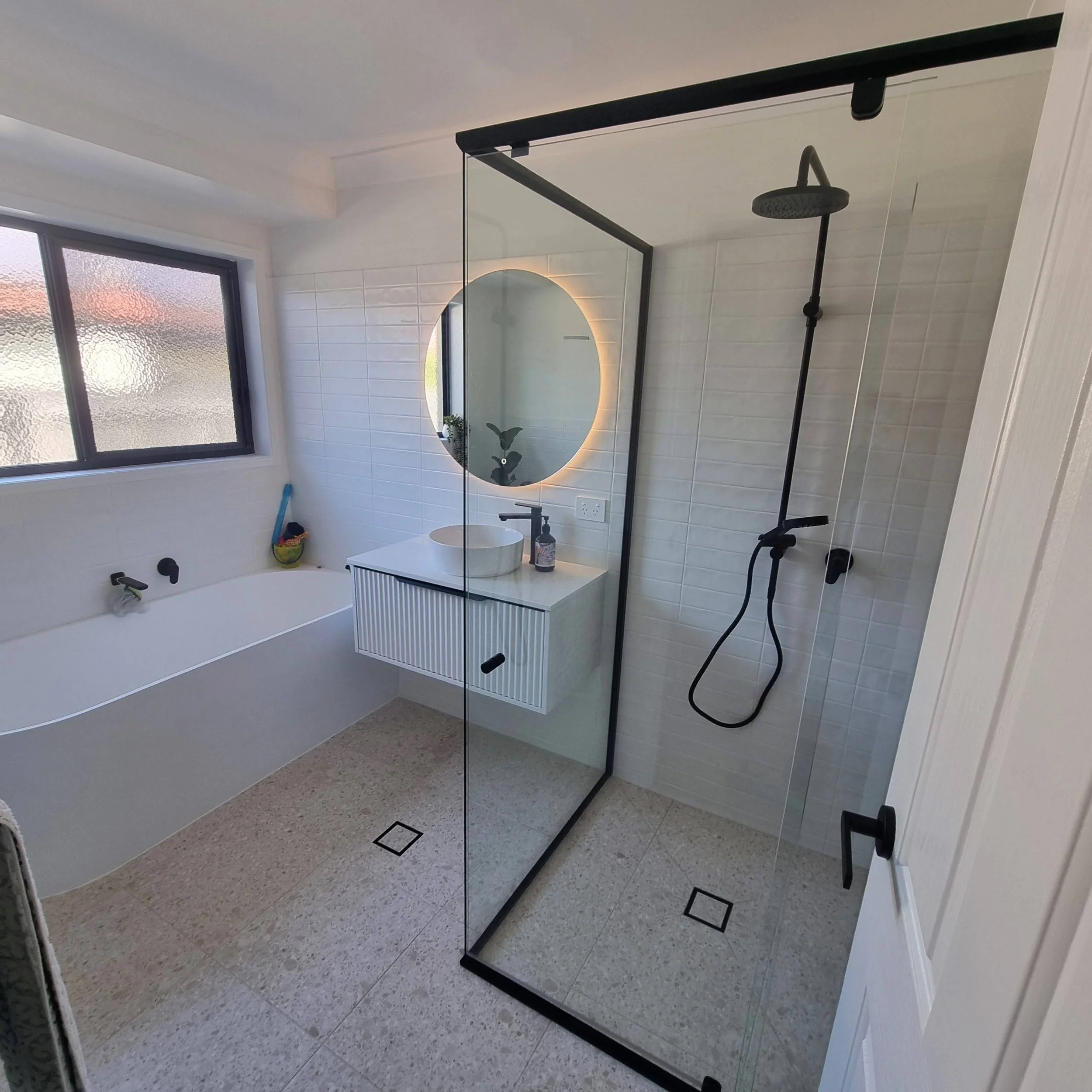 Semi-frameless pivot shower screen with full-height glass panel in modern bathroom