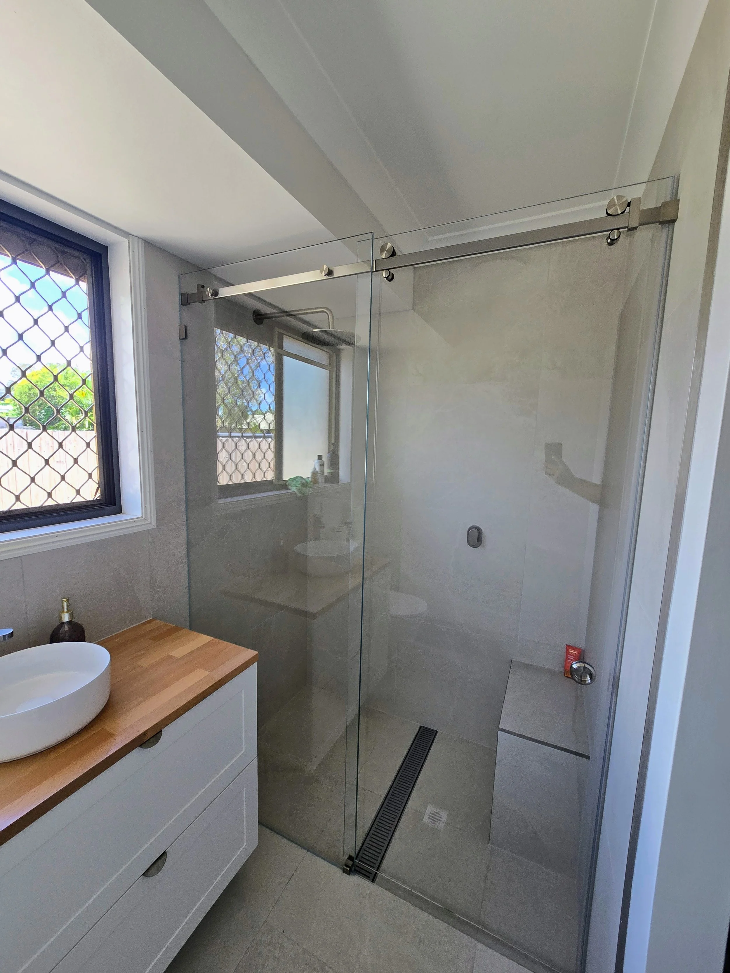 Frameless sliding barn door style shower screen in brushed nickel with low iron Ultraclear glass
