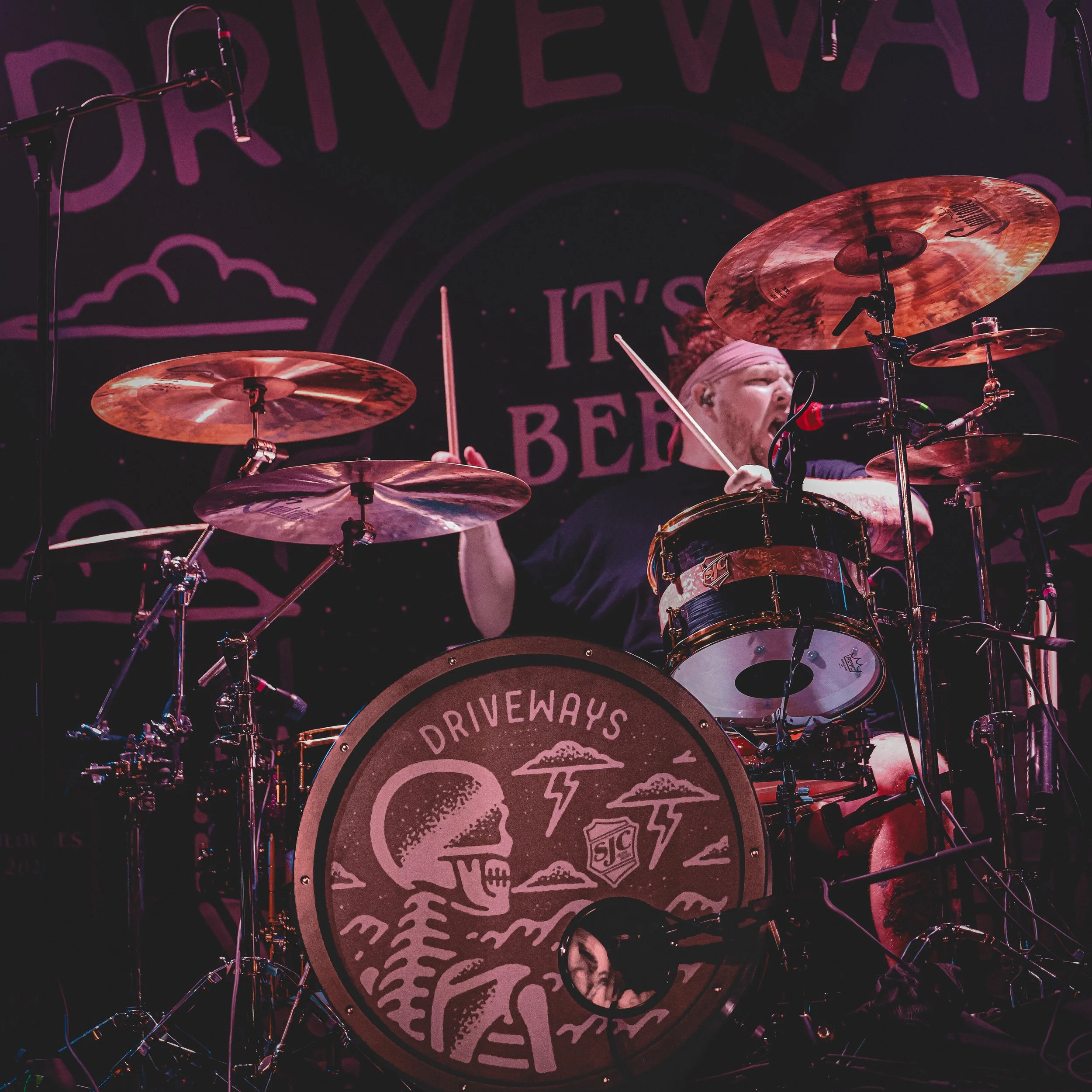 Driveways drummer playing behind the band’s illustrated bass drum during the live set