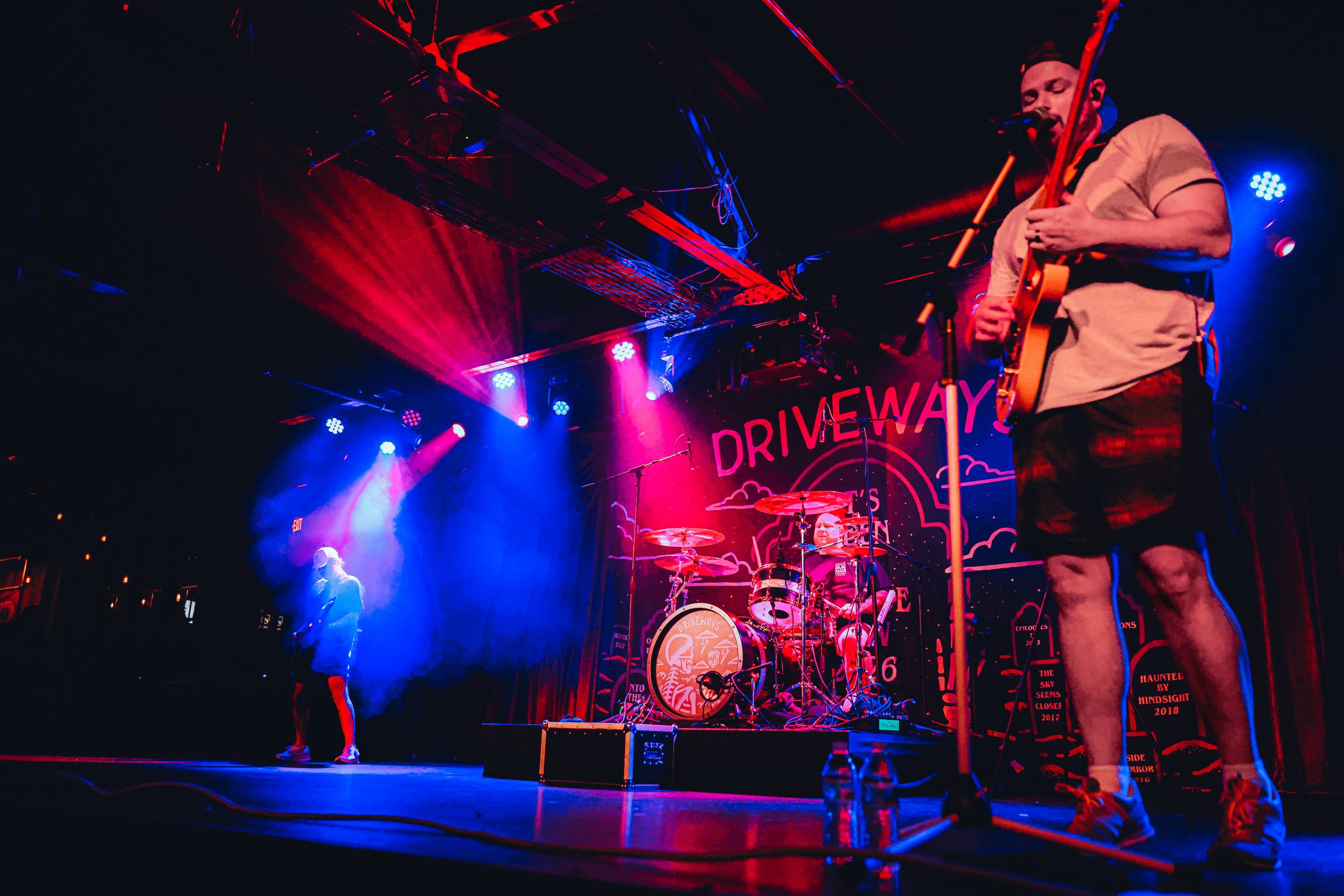Wide view of Driveways performing onstage beneath dramatic red and blue lighting