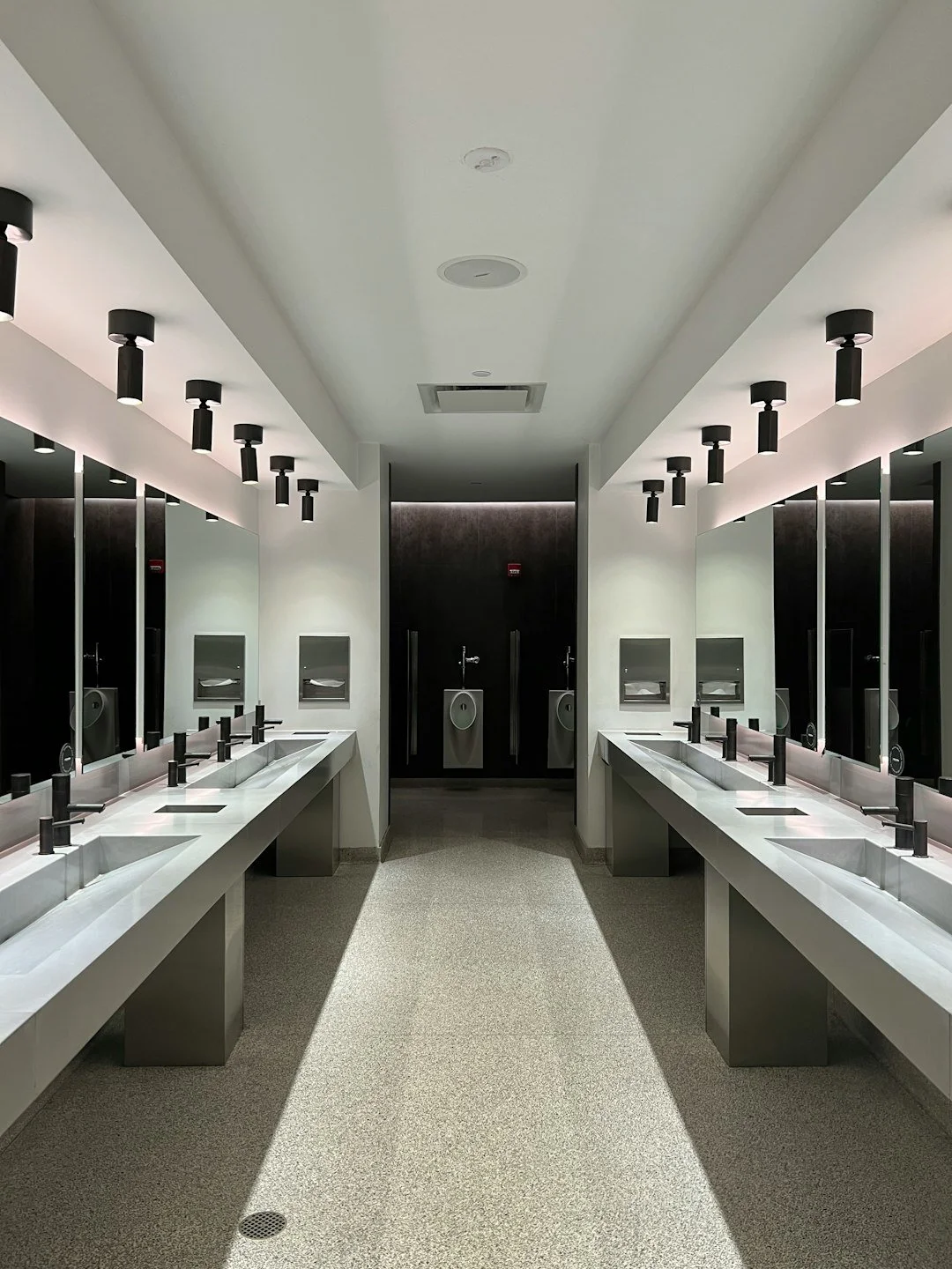 Modern commercial bathroom facility with mirrors, basins, vanity benchtops and tiled flooring