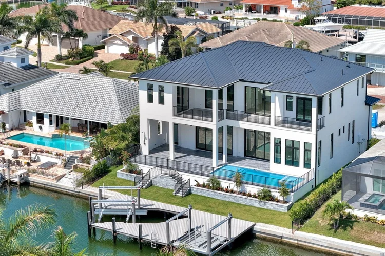 The rear of the house on the canal: pool and spa, lawn, seawall, dock and boat lift.