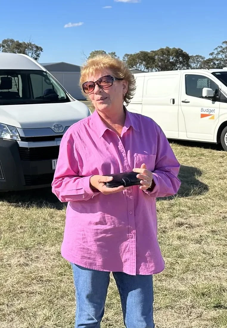 Linda Jesky, smiling in sunglasses and a pink shirt, at a flying field.