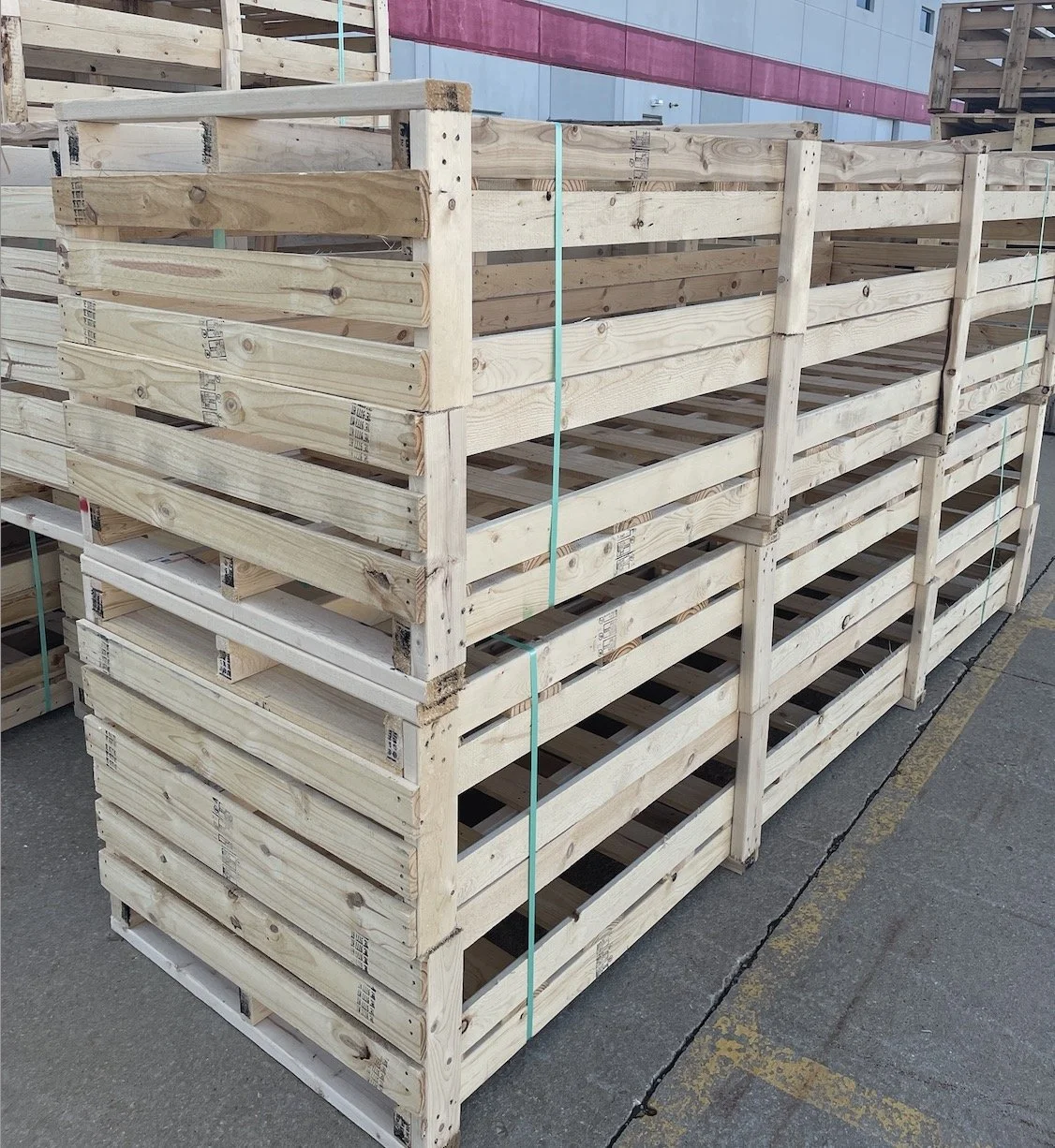 Stacked large custom slat crates staged outside a manufacturing facility
