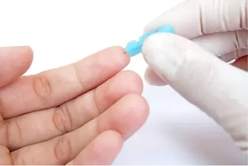 Person completing an at-home finger-stick blood collection