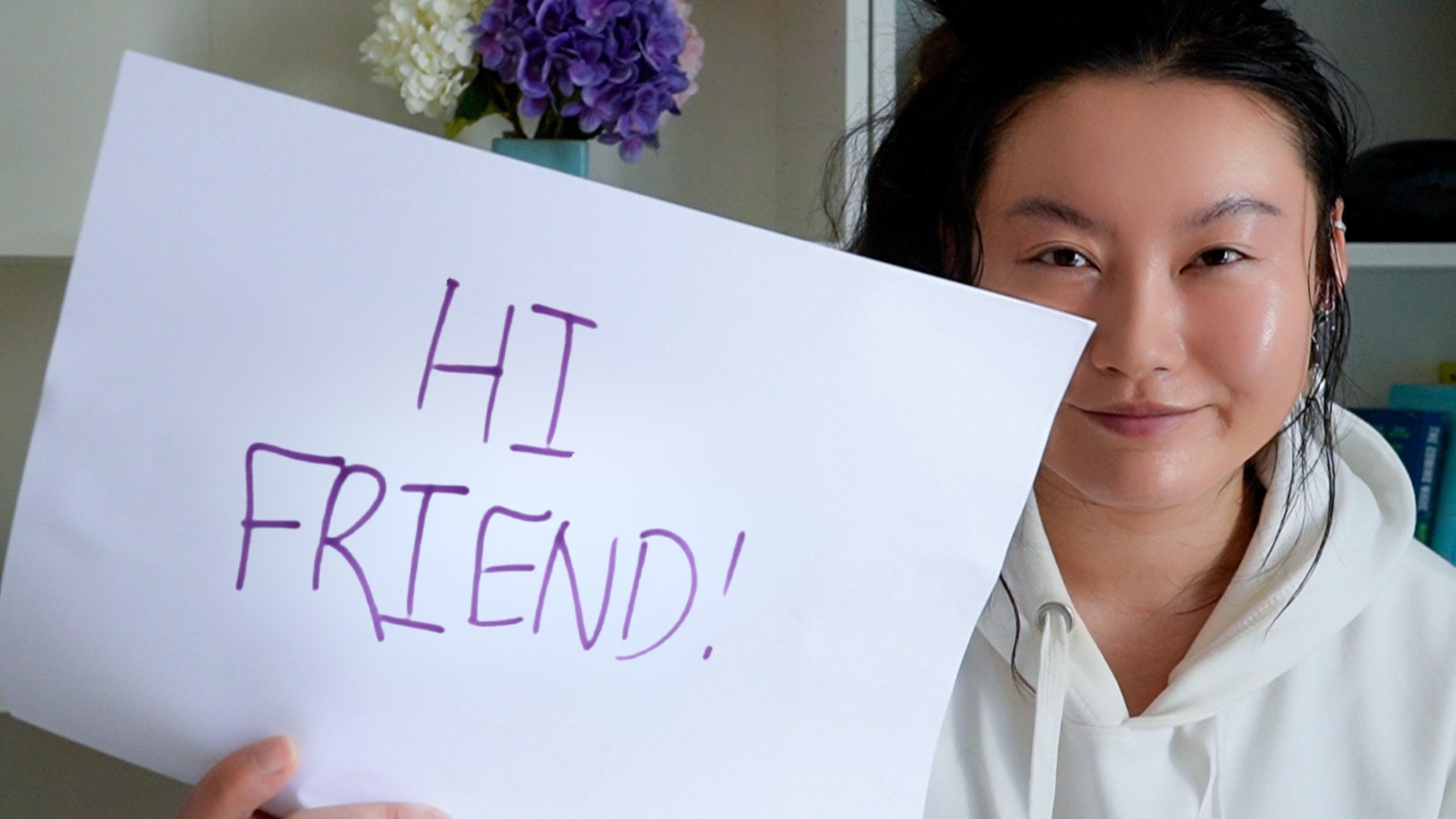 Tina Huang holding a sign that reads Hi friend
