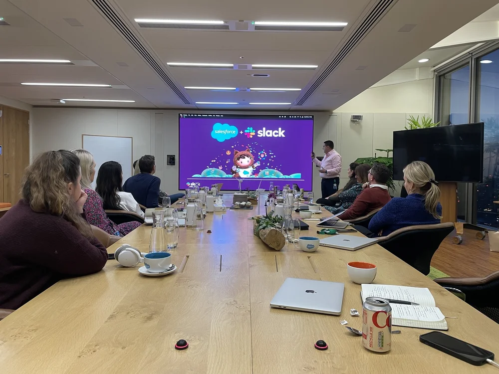 Karl Nicholson presenting beside a Salesforce and Slack screen in a boardroom