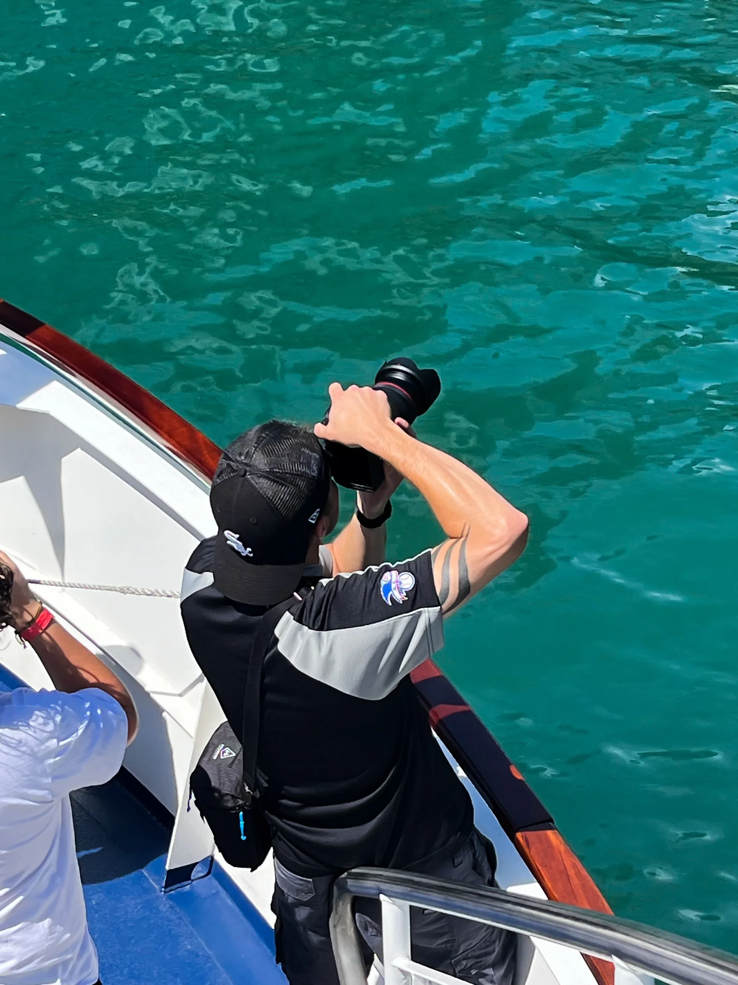 Chris Motte photographing from a boat above turquoise water.