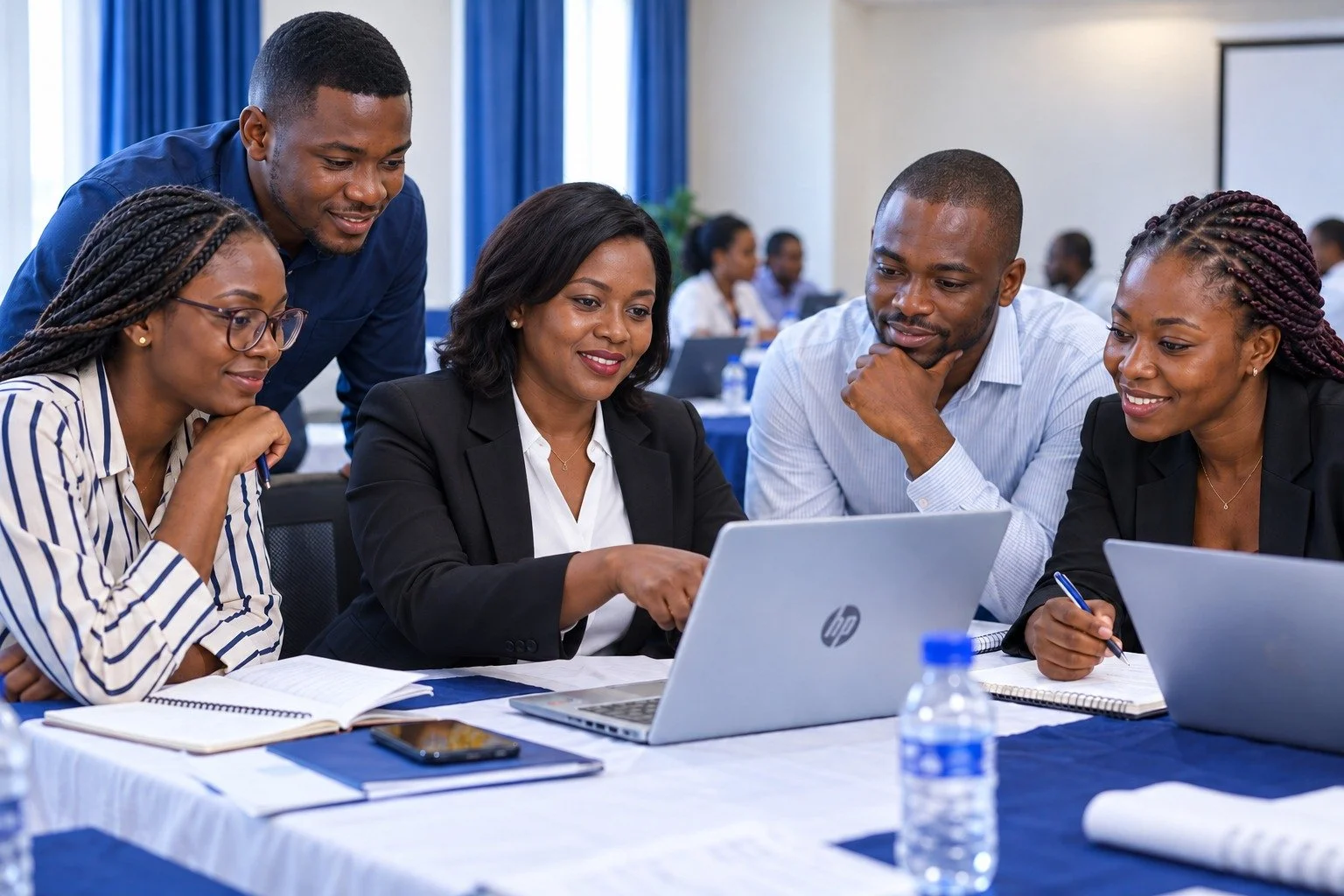 Illustrative scene of a coach guiding young professionals through a laptop exercise.