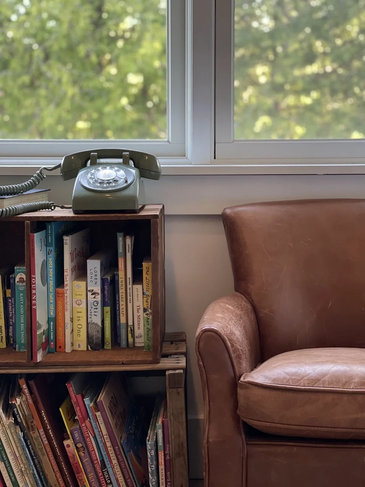 A leather reading chair beside a bookshelf and a vintage telephone