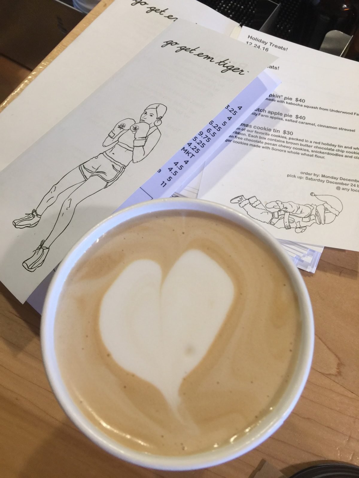 A latte with a heart beside handwritten notes