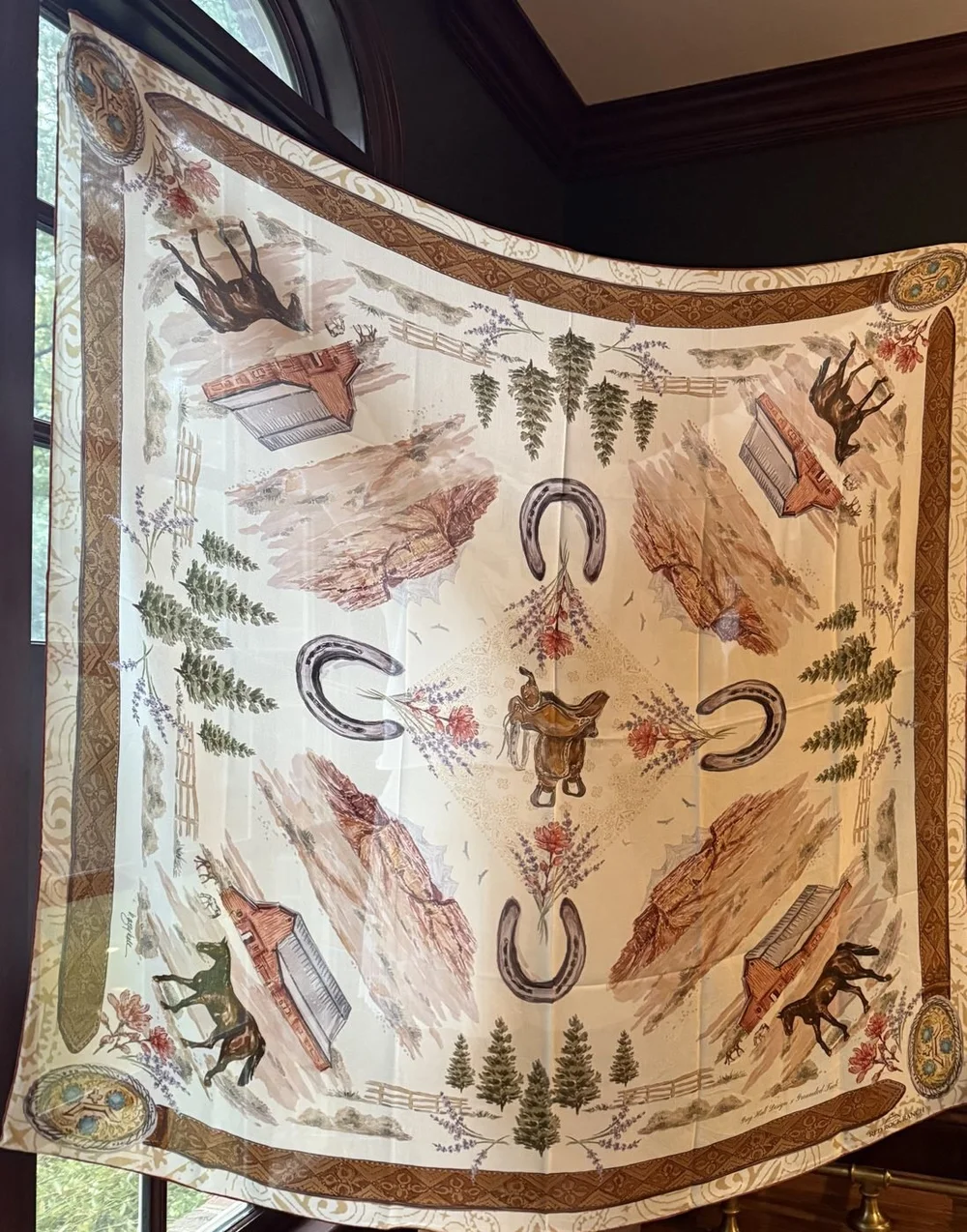 The Red Rock Ranch silk scarf held up in a window