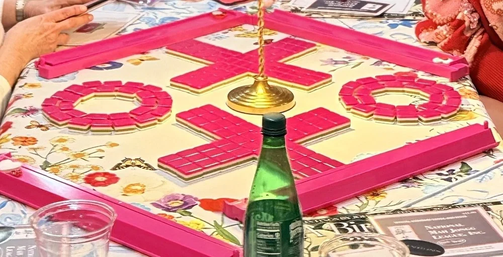 Pink mahjong tiles spelling XOXO on a floral tablecloth