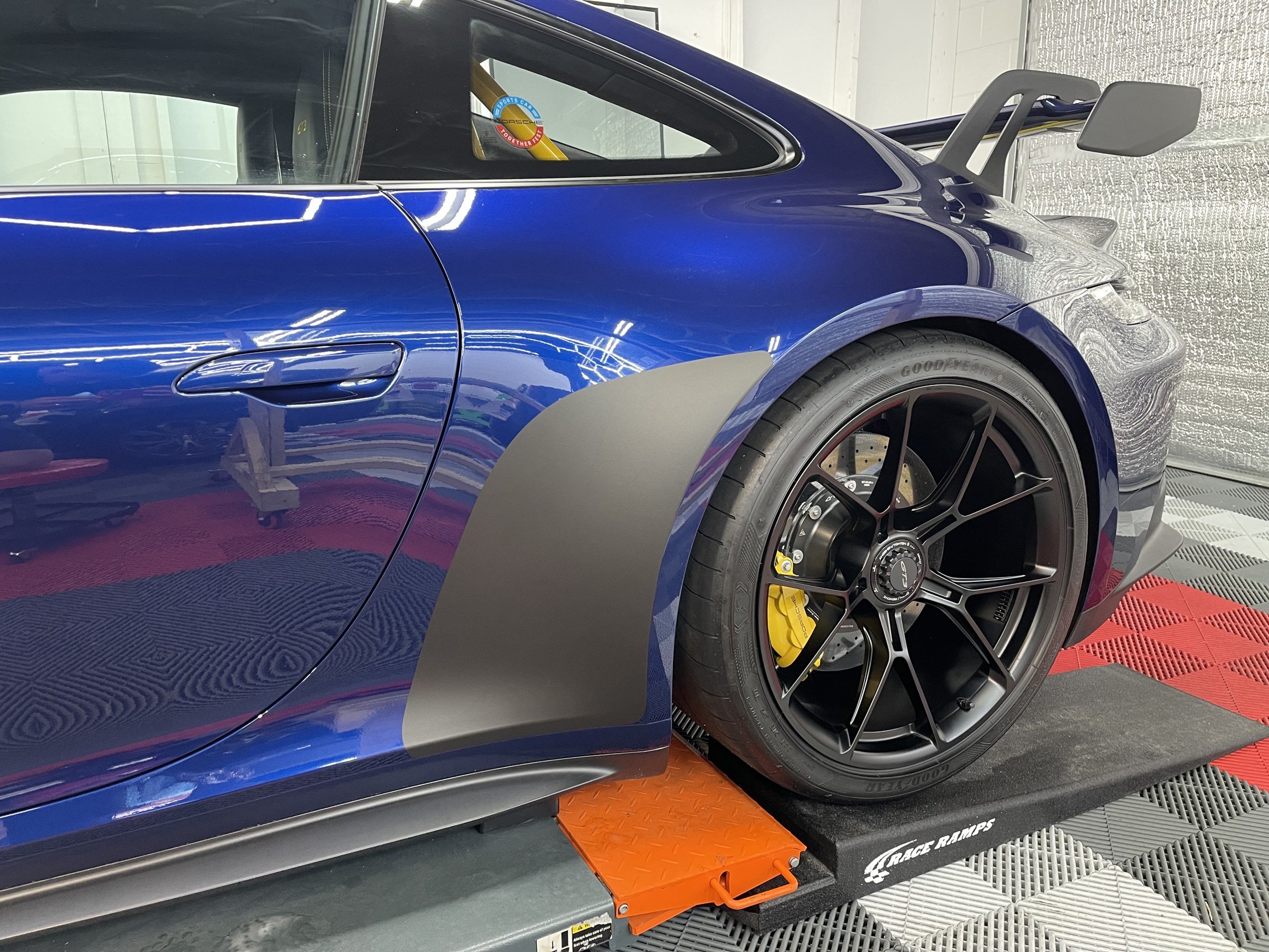Close view of a blue Porsche GT3 rear quarter, wheel and wing inside OCD