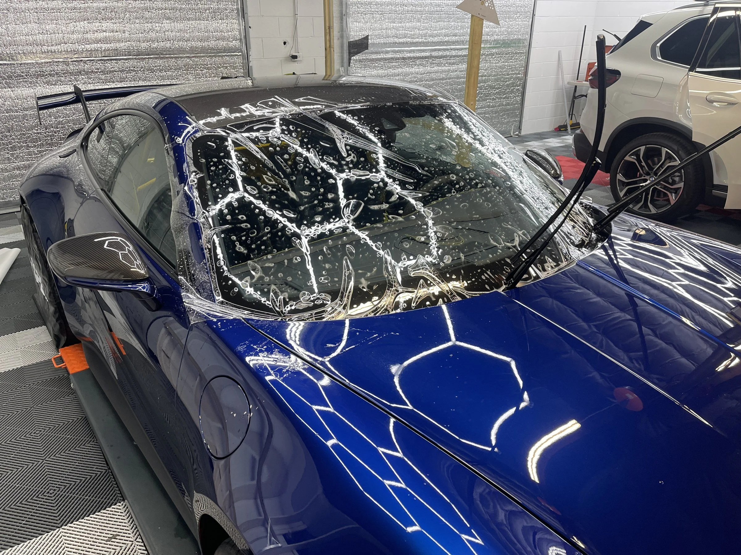 Film being fitted to the windshield of a blue Porsche GT3 in the OCD shop