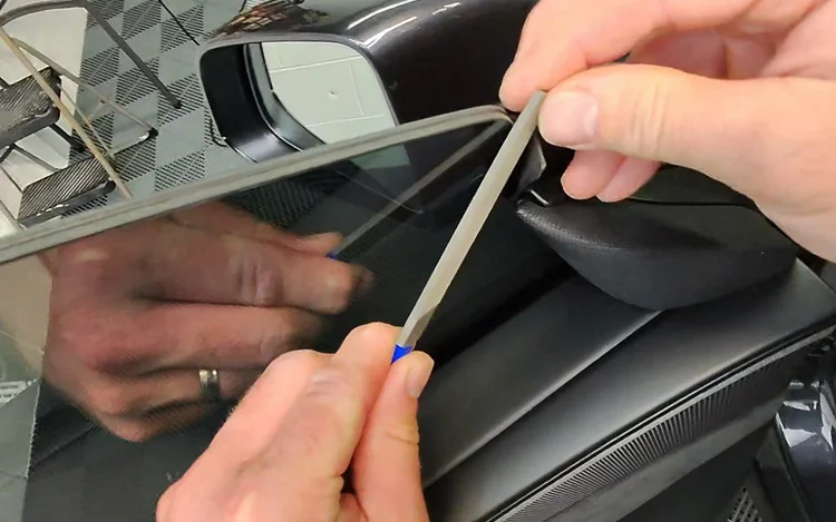 Installer finishing window film inside an open car door.