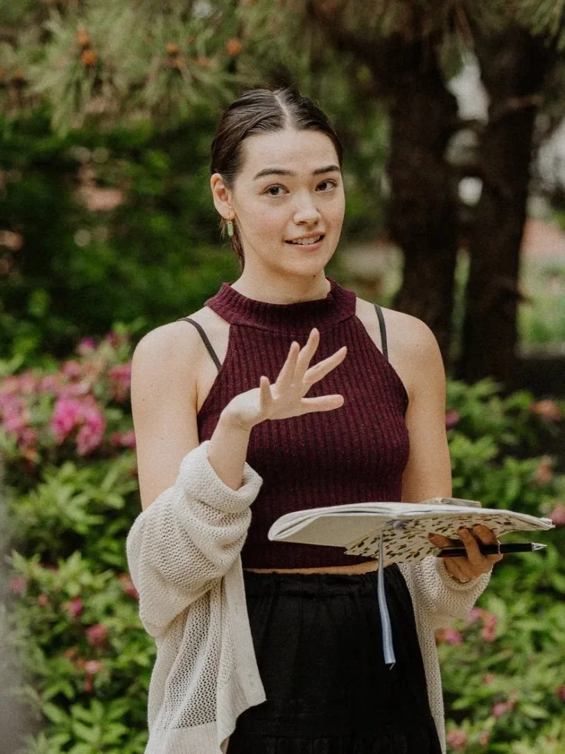 Nina speaking with an open notebook in a garden