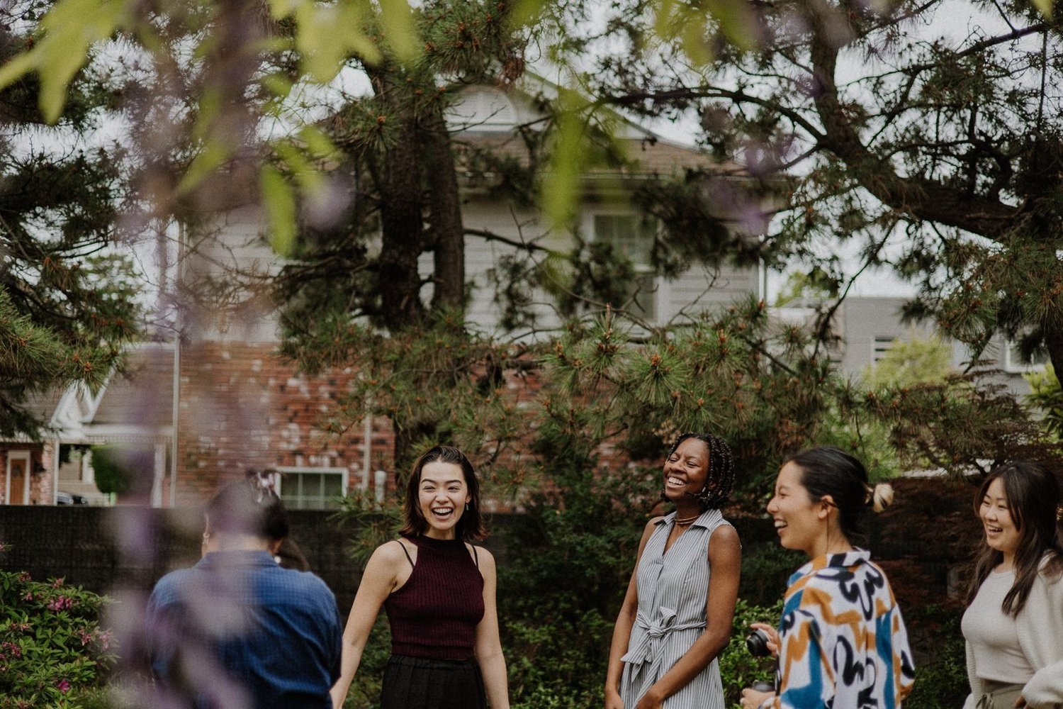 Nina laughing with retreat participants in a garden under pine trees