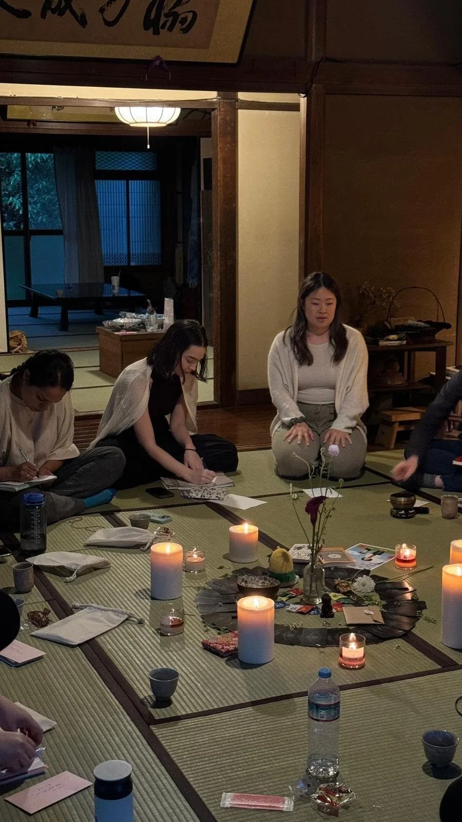 Workshop participants journaling in a candlelit tatami room