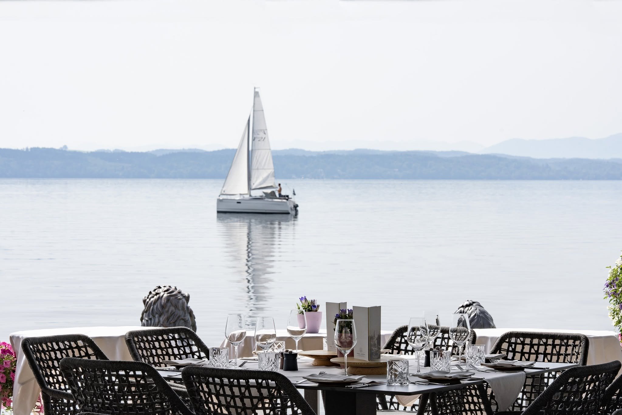 Gedeckte Terrasse am Starnberger See mit Segelboot auf dem Wasser