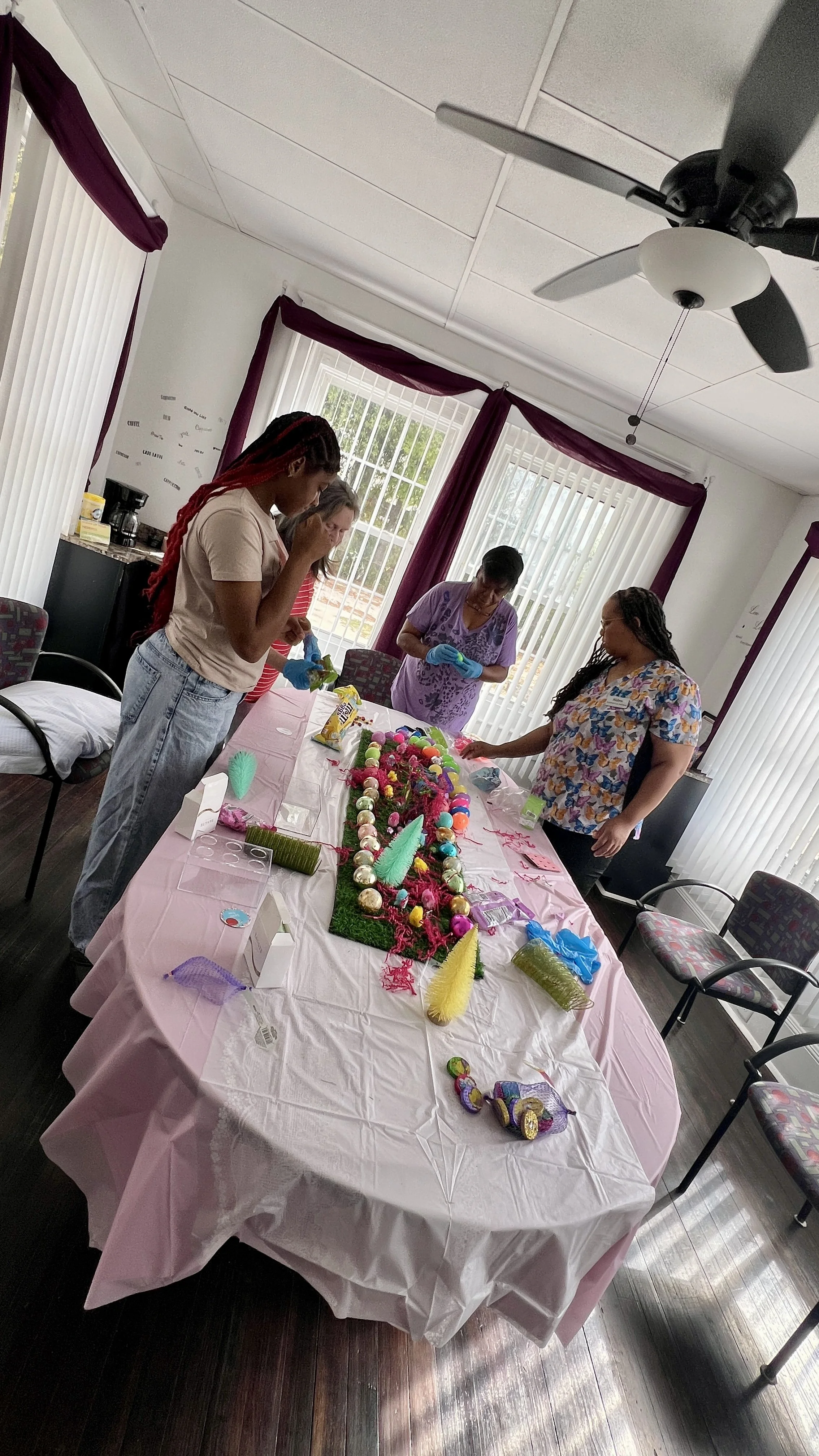 Jazz in denim jacket and spring dress standing proudly at the head of the table beside her completed Easter tablescape and mantle design