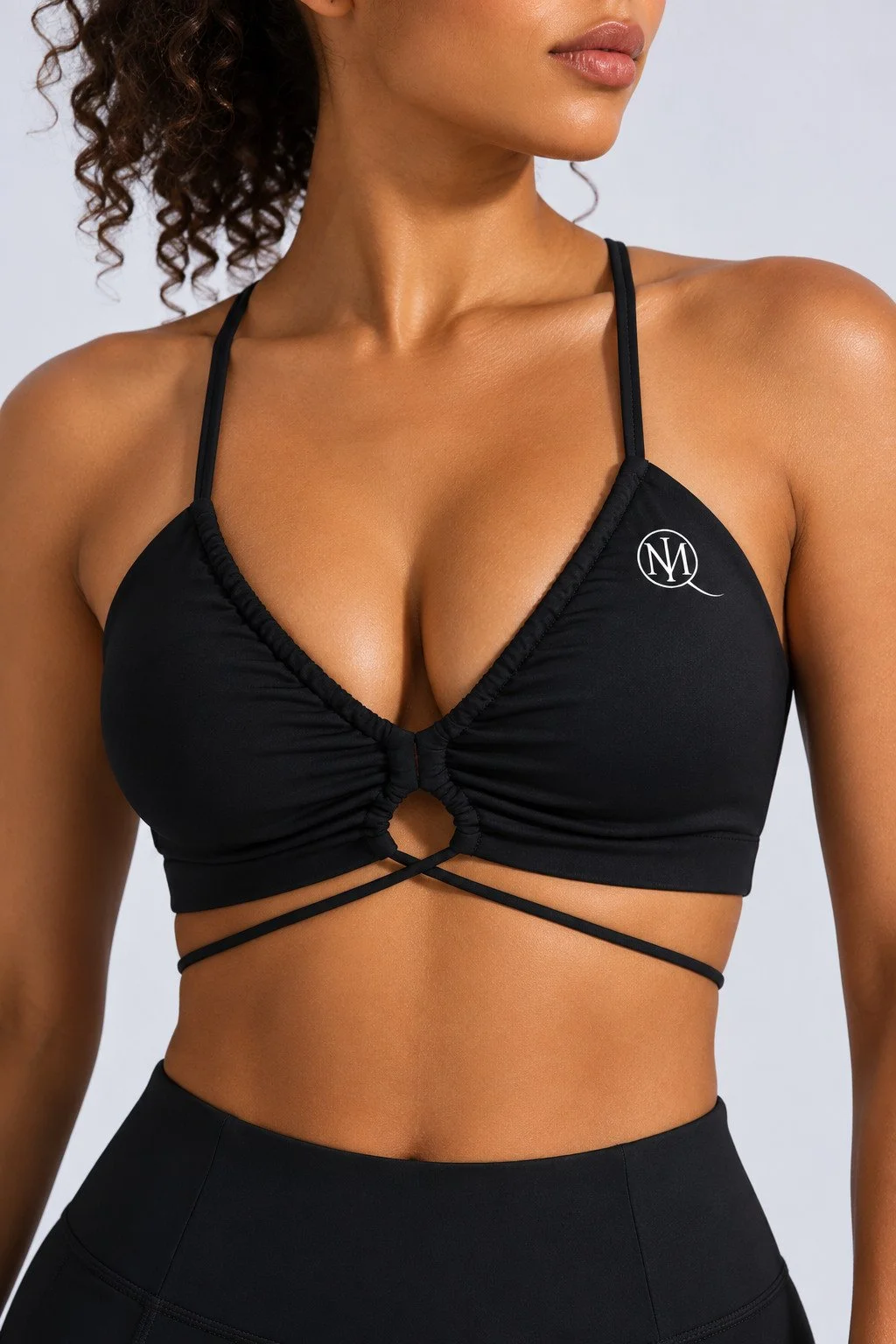 Black MIQ sports bra detail showing original white upper-left chest logo