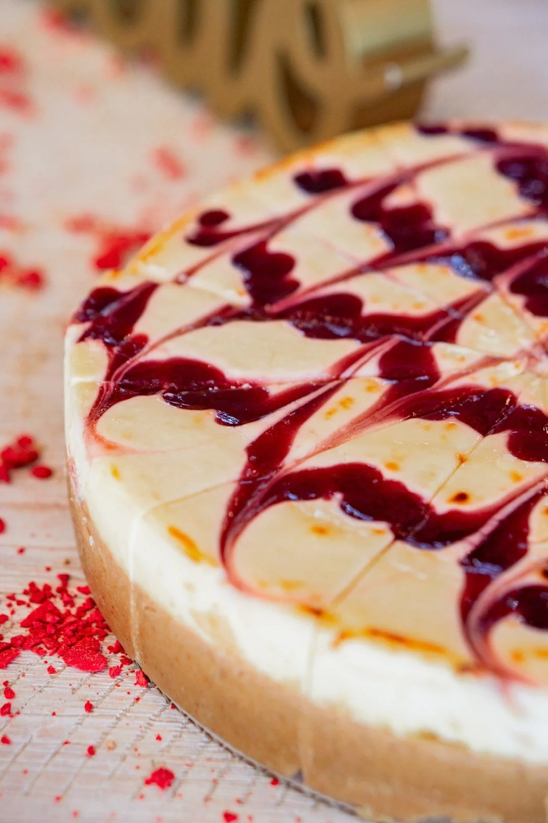 A cheesecake topped with a berry swirl and rose petals