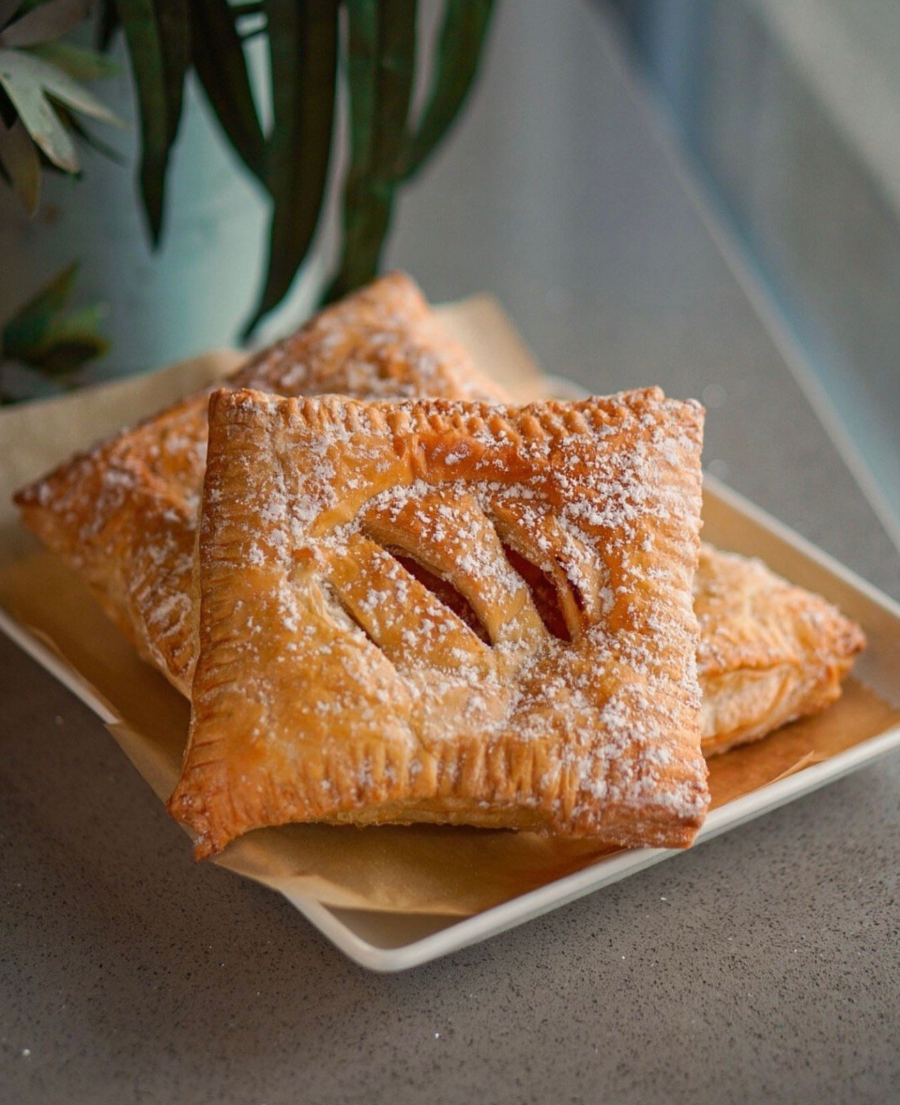 A golden square pastry beside green foliage