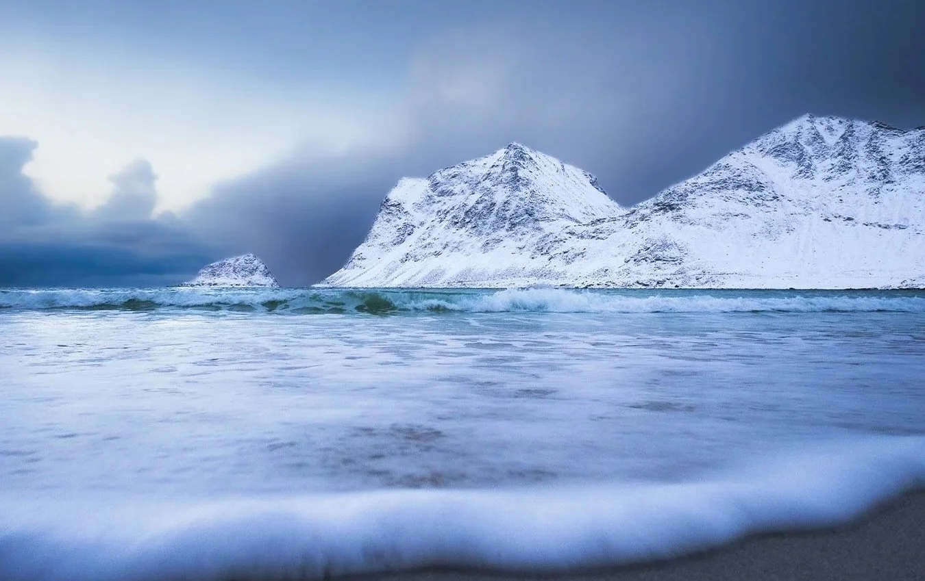 Norwegian mountains meeting the sea beneath a dramatic sky