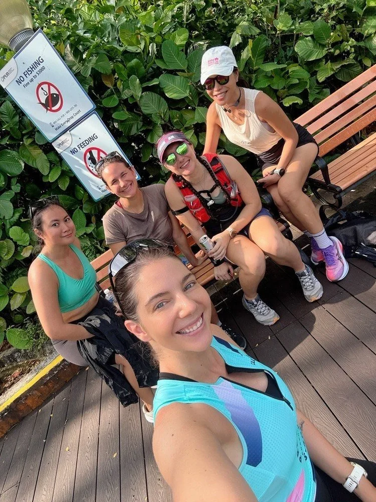 Frankie and four Pretty Strong athletes resting on a bench during a group run in Singapore