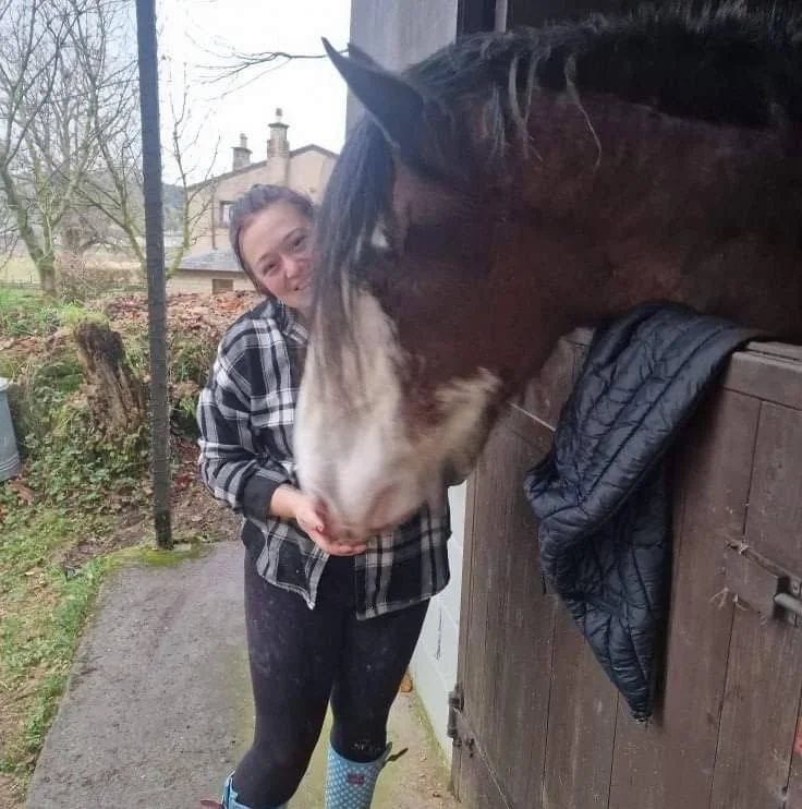A horse and handler sharing a calm moment outside a stable