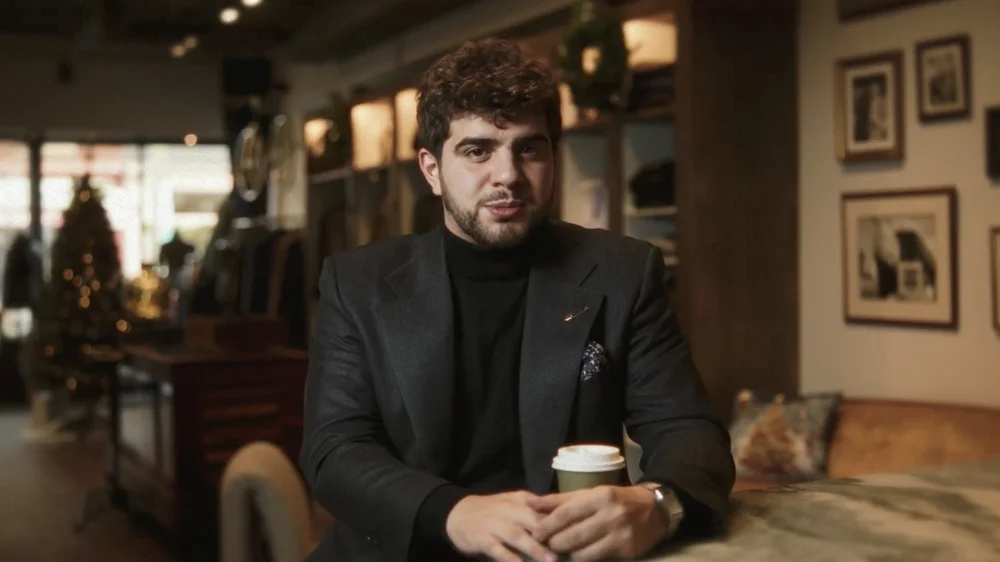 A subject in a dark jacket in a softly lit interview setting