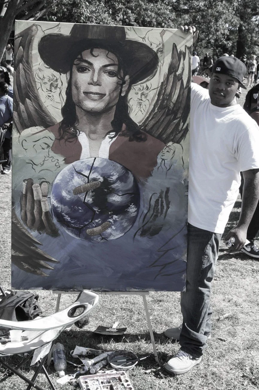 Artist standing beside a hand-painted Michael Jackson portrait