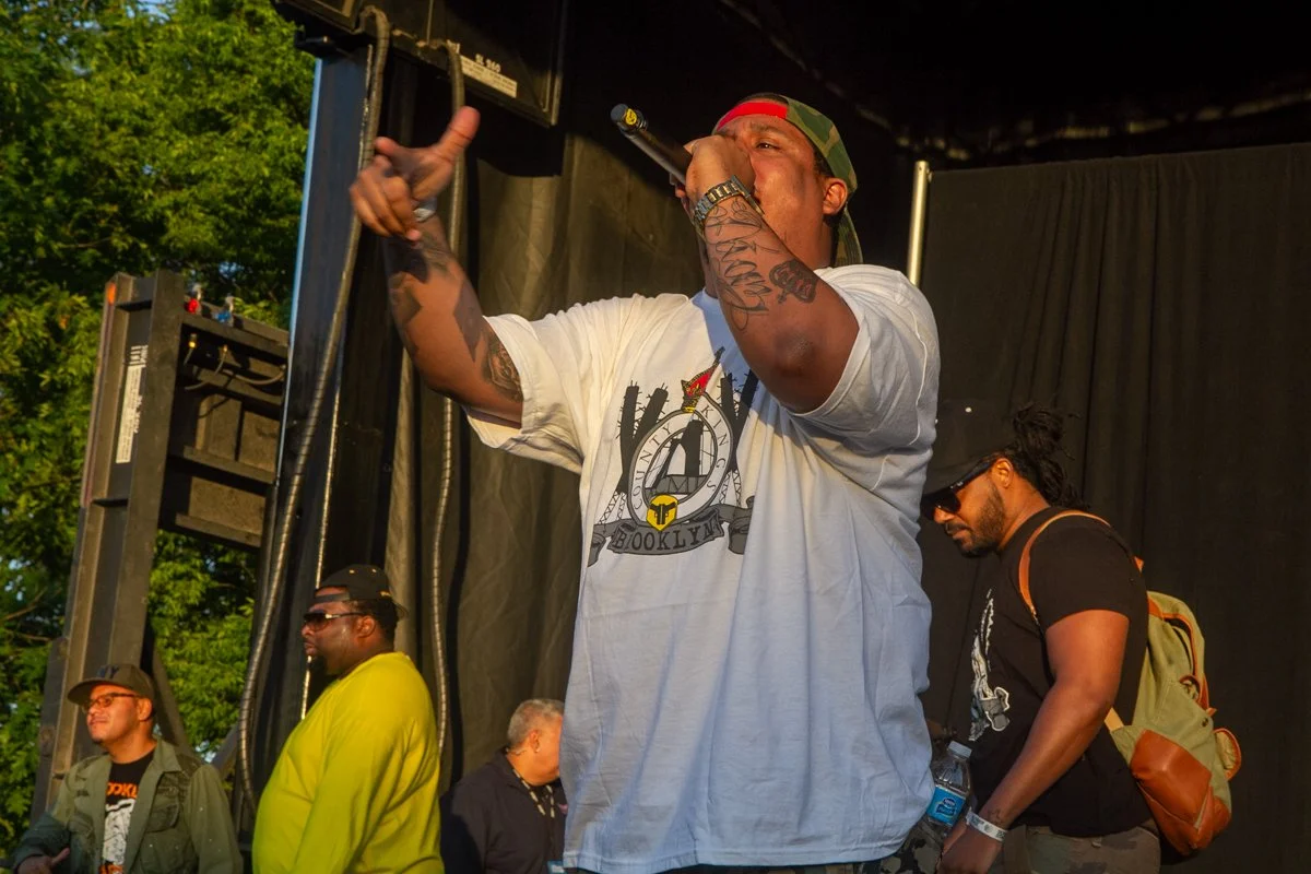 Wide view of Pumpkinhead performing during an outdoor hip-hop concert with fellow artists onstage.