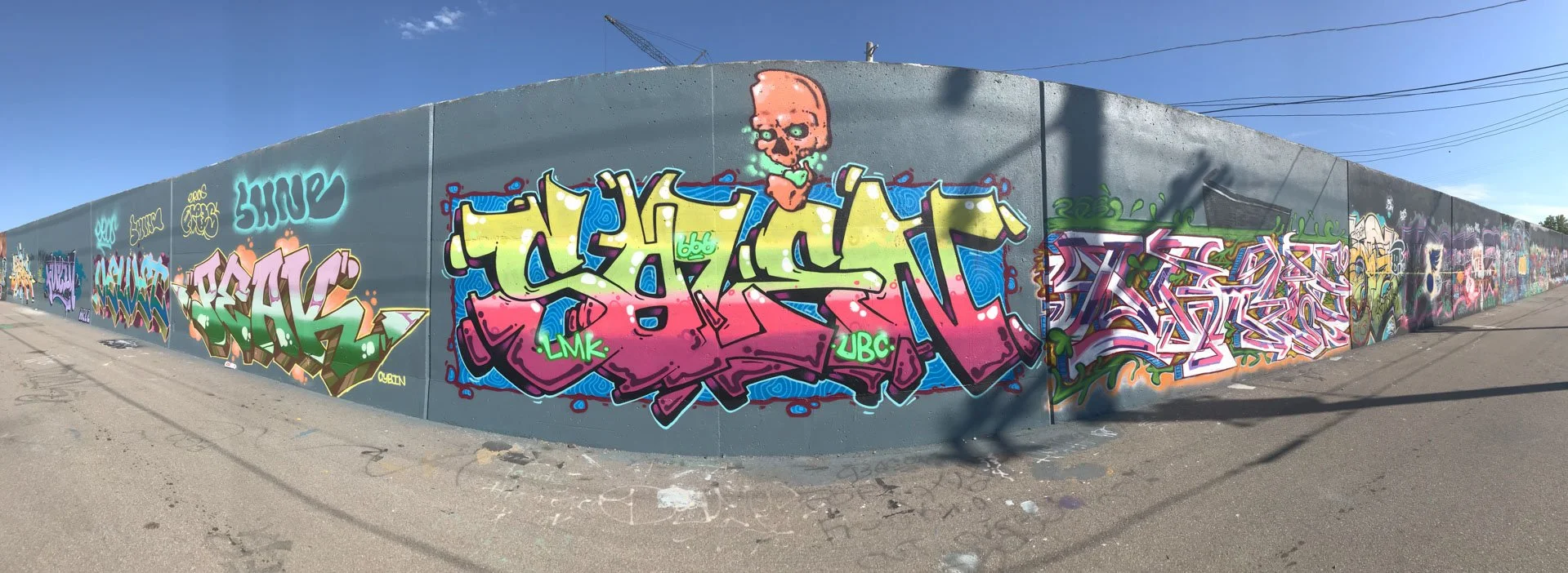 Graffiti lettering in yellow, pink, blue and green with an illustrated skull