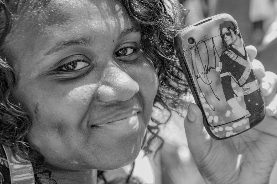 Young woman holding a phone displaying a Michael Jackson tribute image
