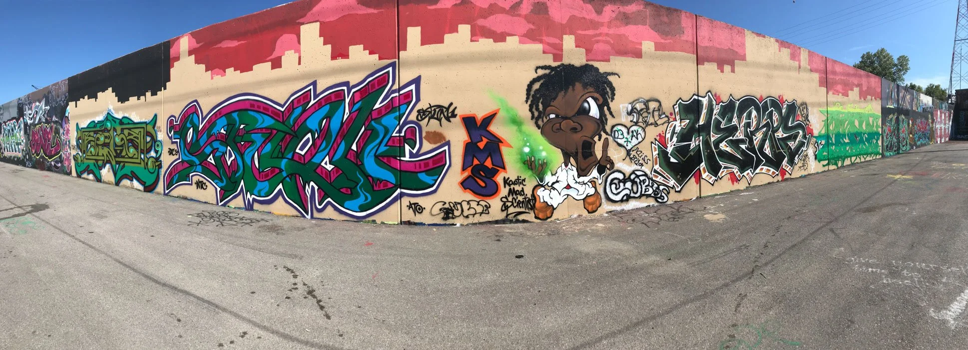 Panoramic section of the Mural Mile with colorful graffiti lettering and a painted character