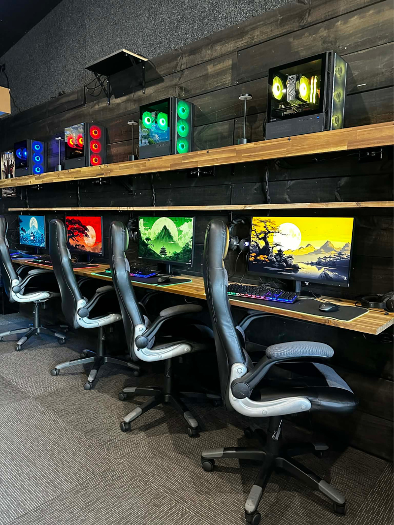 Row of high-spec gaming PCs set up in a lounge with ambient lighting
