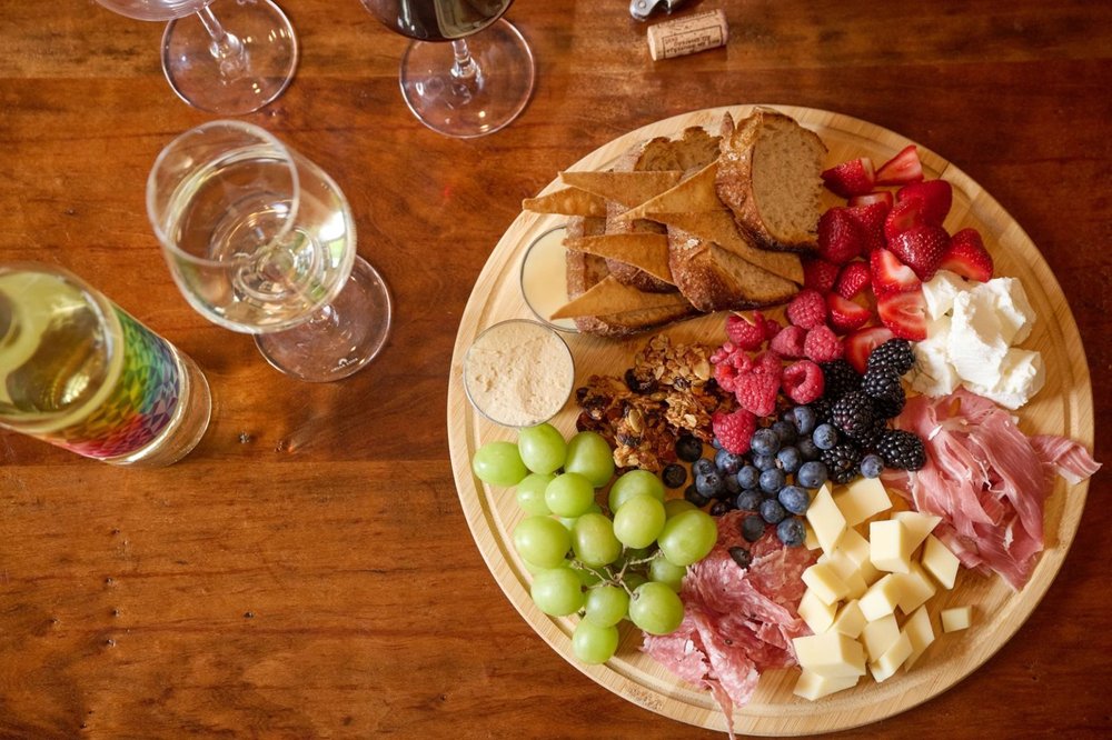 Cheese and charcuterie board with fresh berries, grapes and bread