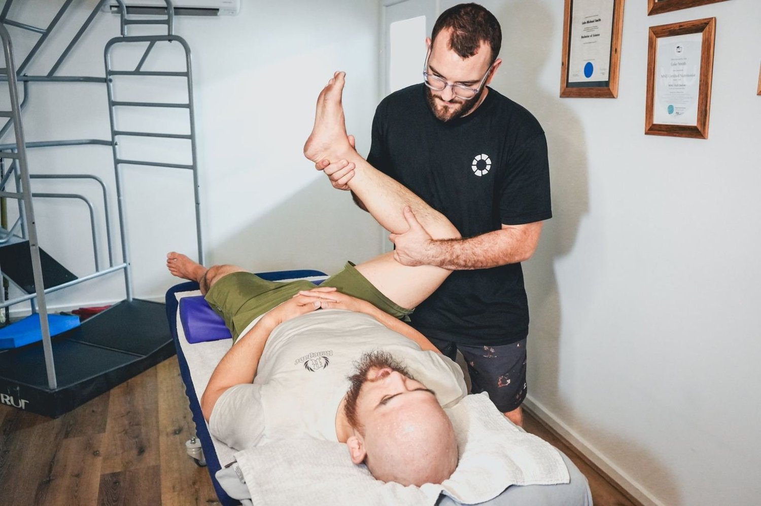 Dr Luke Smith assessing a patient's hip and hamstring on the treatment table at Mixed Osteo, Kensington
