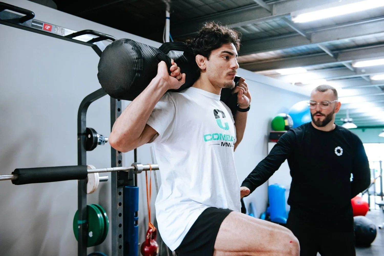 Dr Luke Smith coaching an athlete through a loaded lunge during a strength-based rehab session