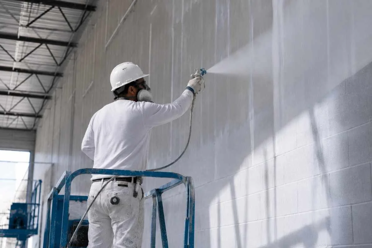 Eagle Crest painter using an airless spray system on a large commercial exterior wall in Ontario