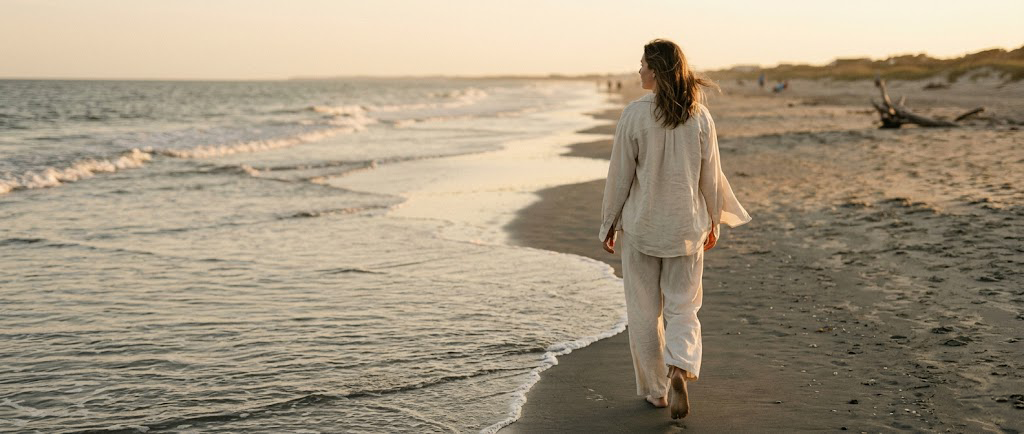 Woman walking the Isle of Palms shoreline at golden hour at The Way Home retreat