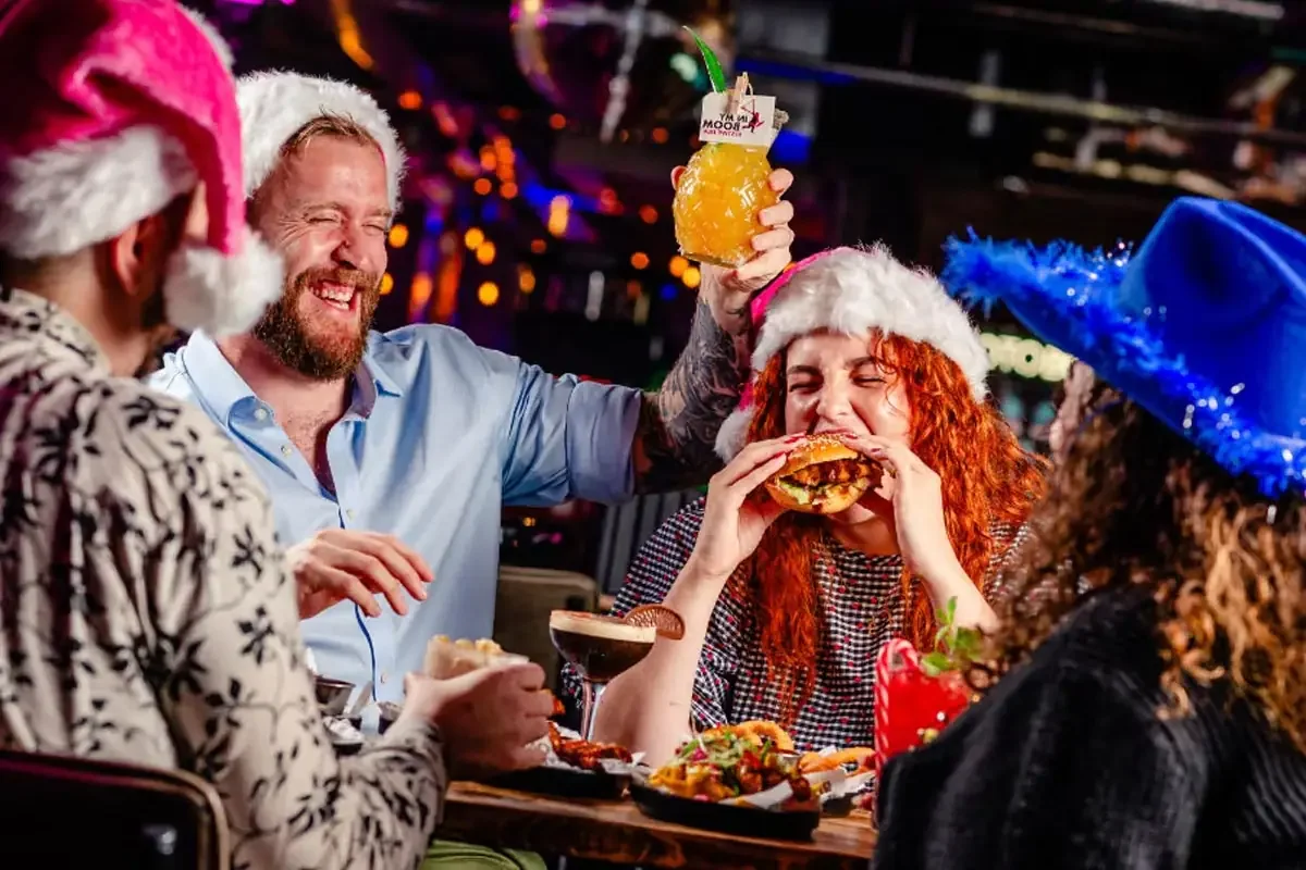 Friends celebrating Christmas with food and cocktails at BOOM BATTLE BAR.