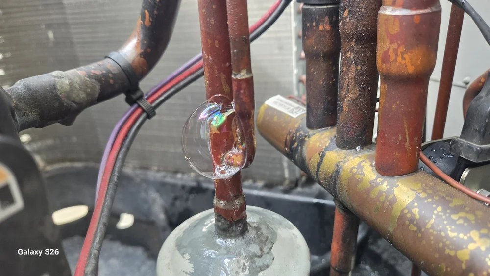 Bubbles at a leaking refrigerant-line connection during AC leak detection in Doral
