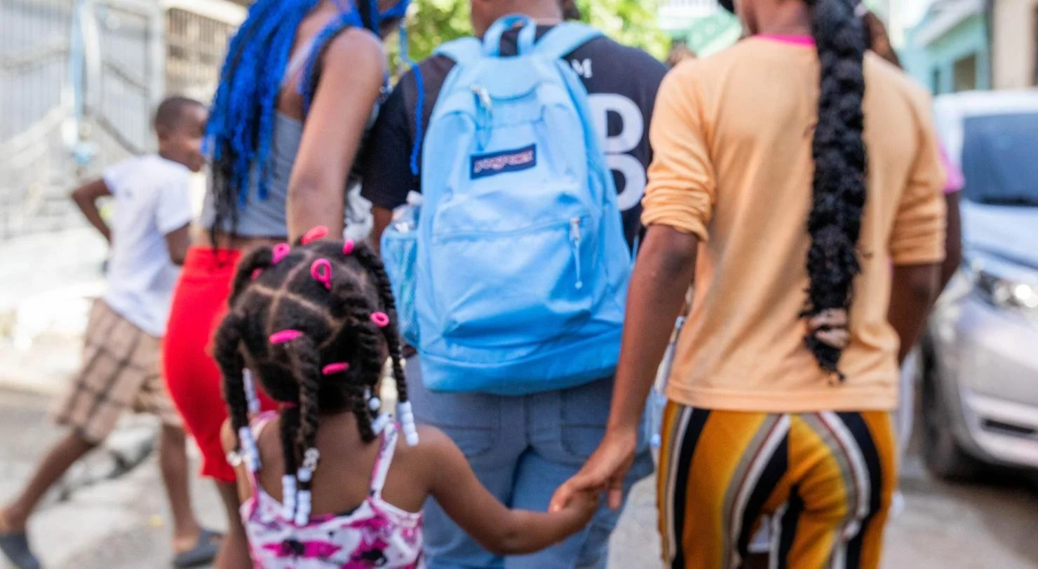 A team member walks hand in hand with a young girl through the neighborhood